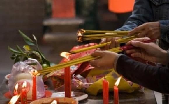 Những bàn tay đang thắp hương và nến, tượng trưng cho sự chuẩn bị lòng thành kính cho lễ cúng Rằm.