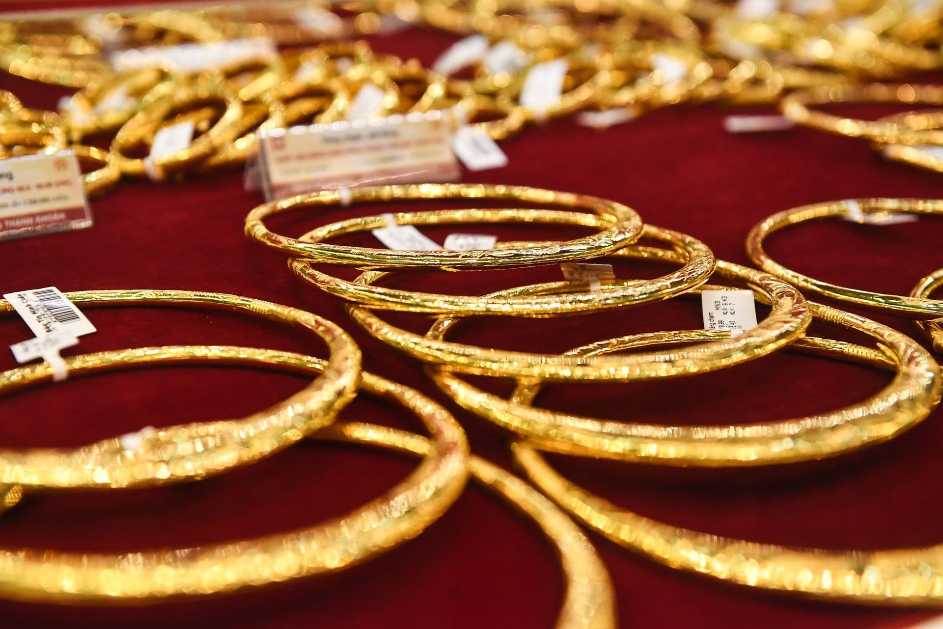 Những chiếc vòng và trang sức vàng 24K được trưng bày trên nền vải đỏ, tượng trưng cho giá trị tích lũy và kênh trú ẩn an toàn của người Việt.