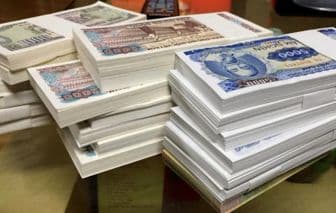 Những chồng tiền Việt Nam, tượng trưng cho cát-xê và biến động kinh tế ảnh hưởng đến thị trường biểu diễn Tết.