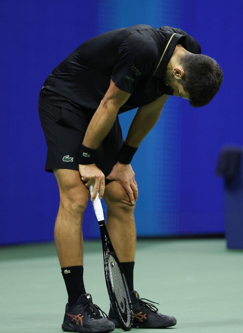 Novak Djokovic cúi đầu, thể hiện sự mệt mỏi hoặc thất vọng sau những khoảnh khắc căng thẳng trên sân đấu US Open.