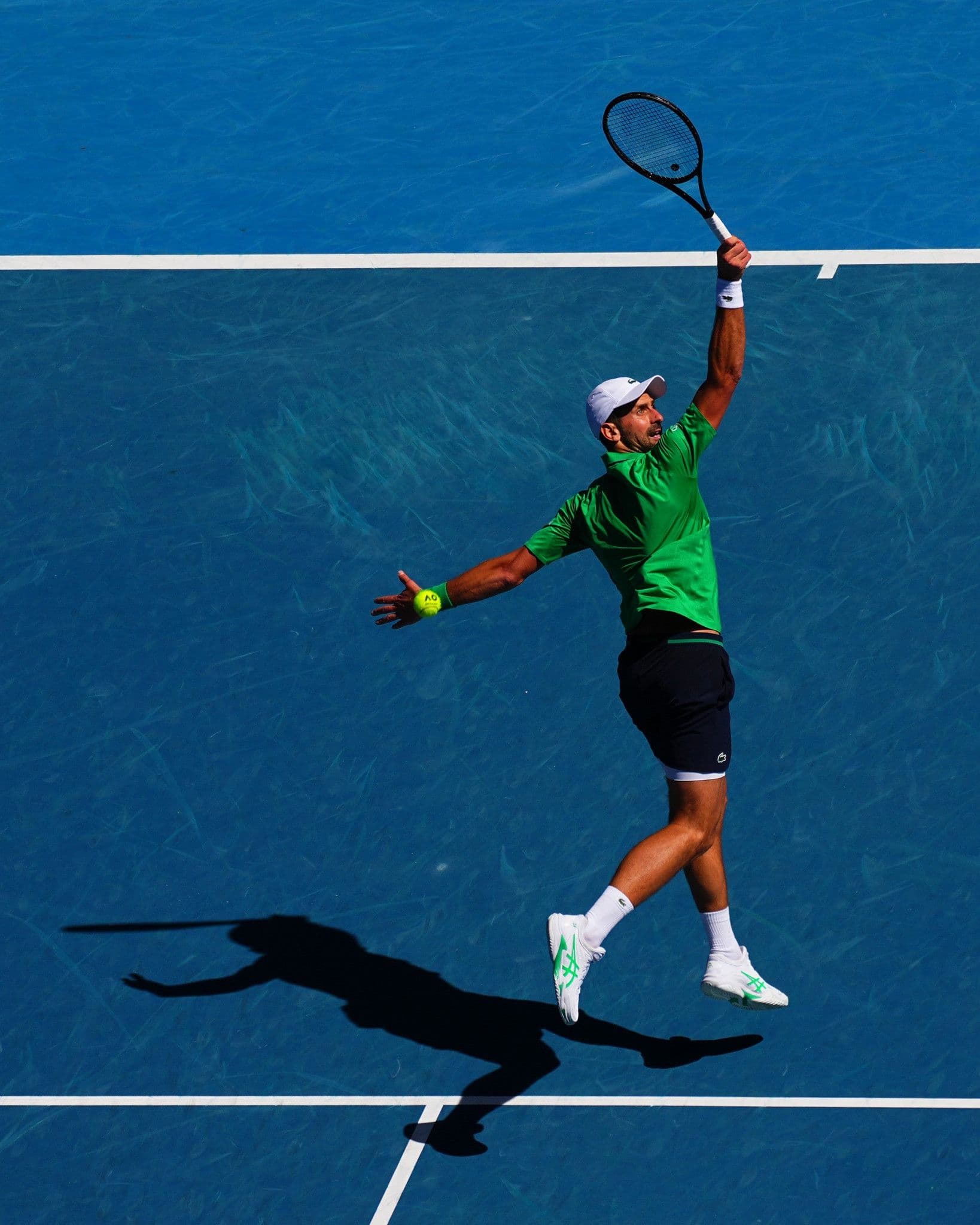 Novak Djokovic giao bóng mạnh mẽ trên sân xanh tại Australian Open 2026.