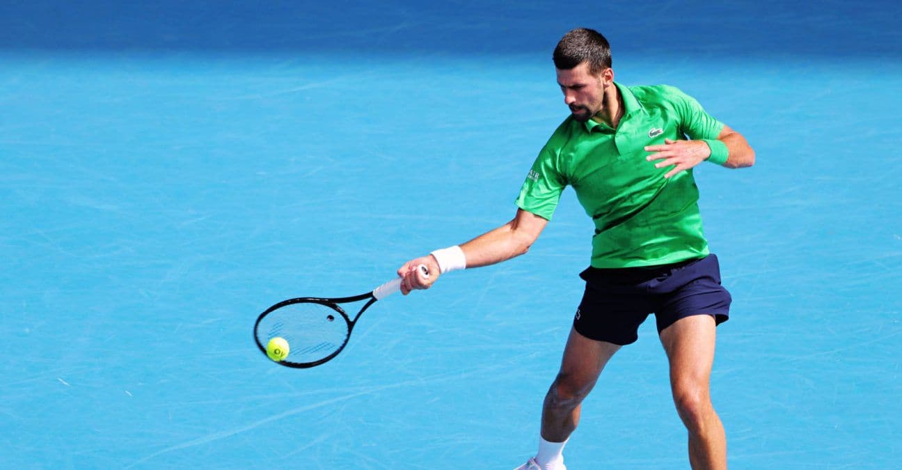 Novak Djokovic đánh bóng trên sân tennis xanh, thể hiện sự quyết tâm và phong độ.