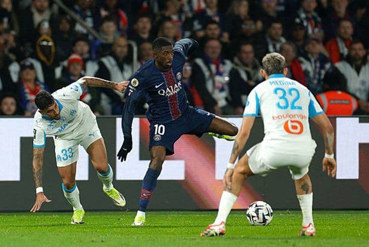 Ousmane Dembele của PSG đi bóng qua hai hậu vệ Marseille, thể hiện kỹ năng tấn công sắc bén.