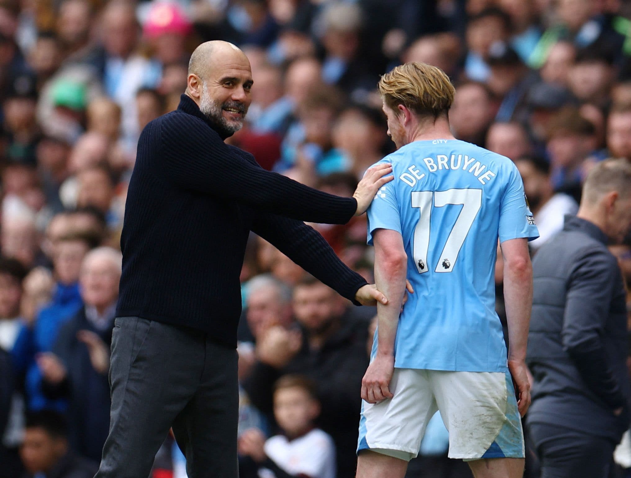 Pep Guardiola tươi cười trò chuyện với Kevin De Bruyne trên sân, thể hiện khả năng lãnh đạo ấm áp và truyền cảm hứng.