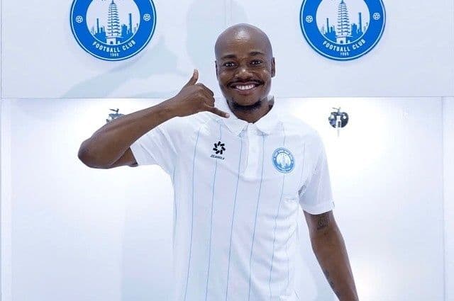 Percy Tau mỉm cười trong áo đấu CLB Nam Định, ra dấu hiệu 'gọi cho tôi'.