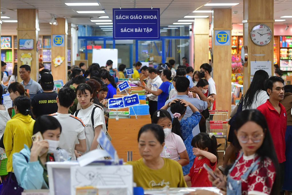 Phụ huynh và học sinh chen chúc tìm mua sách giáo khoa tại nhà sách, thể hiện tình trạng khan hiếm sách.