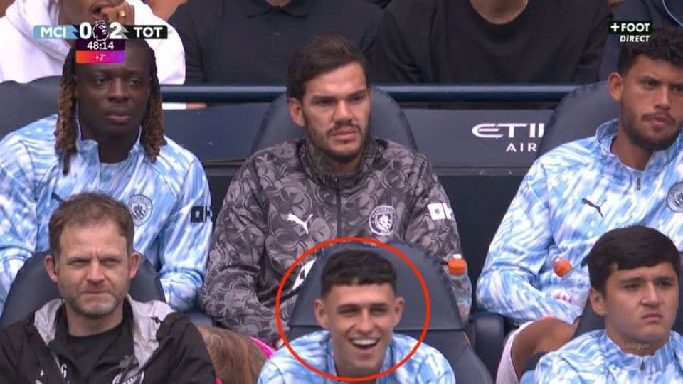 Phil Foden (khoanh tròn) nở nụ cười khó hiểu trên băng ghế dự bị Man City, trong khi các đồng đội thất vọng sau bàn thua thứ hai.