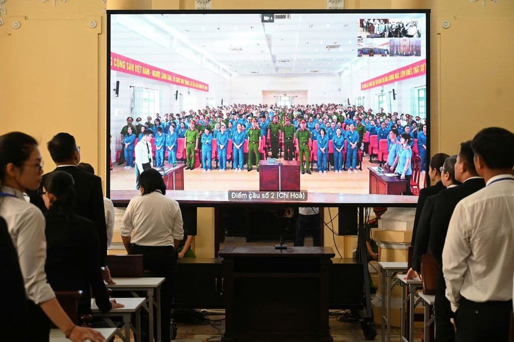 Phiên tòa xét xử trực tuyến với hình ảnh các bị cáo tại trại tạm giam, phản ánh thực tiễn tư pháp hiện đại.