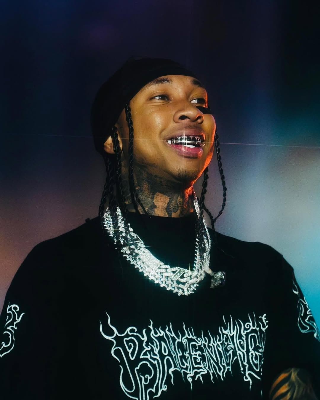 Rapper Tyga với nụ cười tự tin và grillz, thể hiện phong cách hip-hop đặc trưng.
