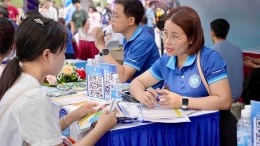 Sinh viên tìm hiểu thông tin tại gian hàng tuyển sinh đại học, thể hiện tác động của chính sách tiền lương đến lựa chọn ngành nghề.