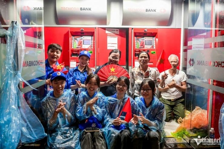 Sinh viên tình nguyện và người dân trú mưa trong cây ATM, cùng hát vang ca khúc cách mạng trong buổi tổng duyệt.