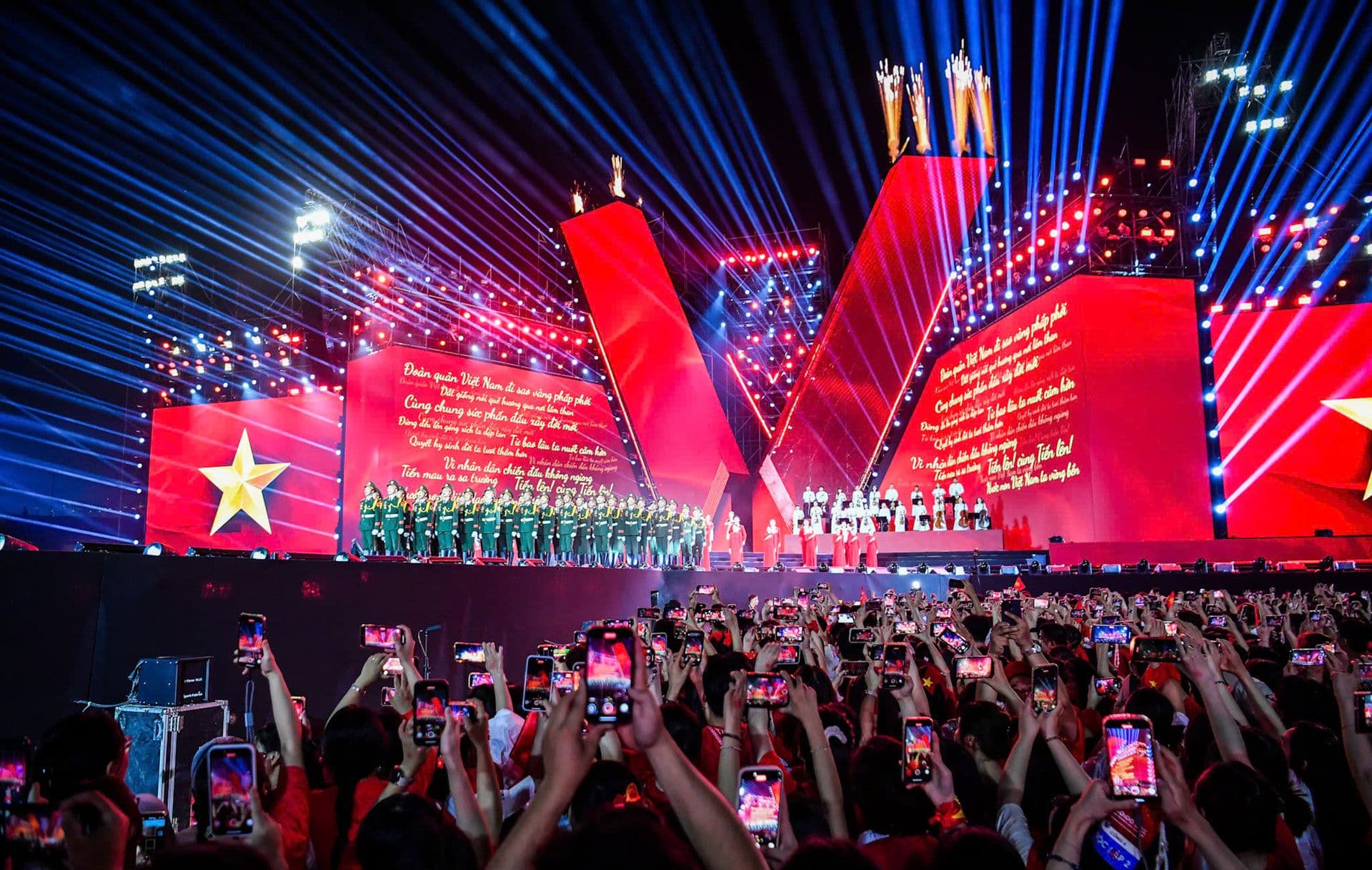Sân khấu concert lớn với ánh đèn rực rỡ và đông đảo khán giả đang ghi hình, thể hiện sự bùng nổ của nhạc Việt.