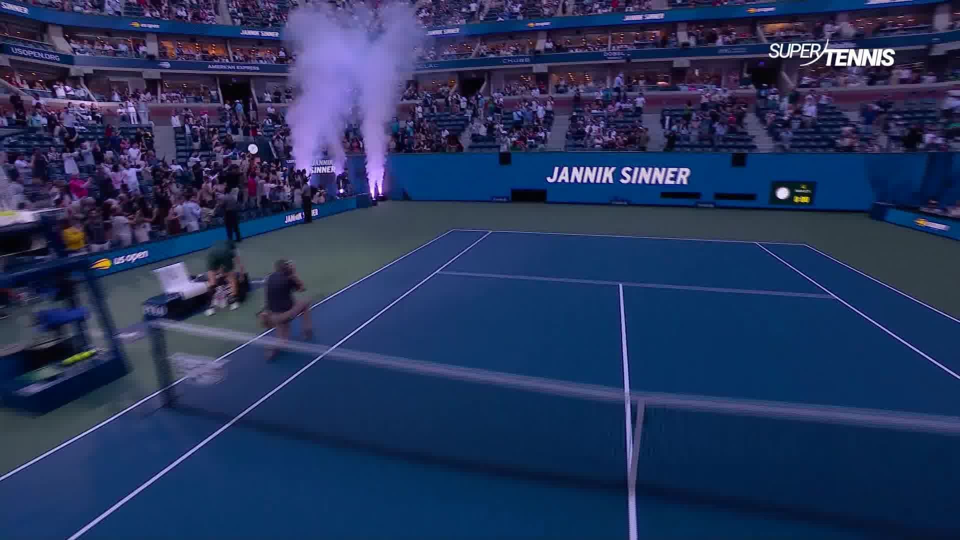 Sân quần vợt US Open với tên Jannik Sinner và hiệu ứng khói, thể hiện không khí hoành tráng của giải Grand Slam.
