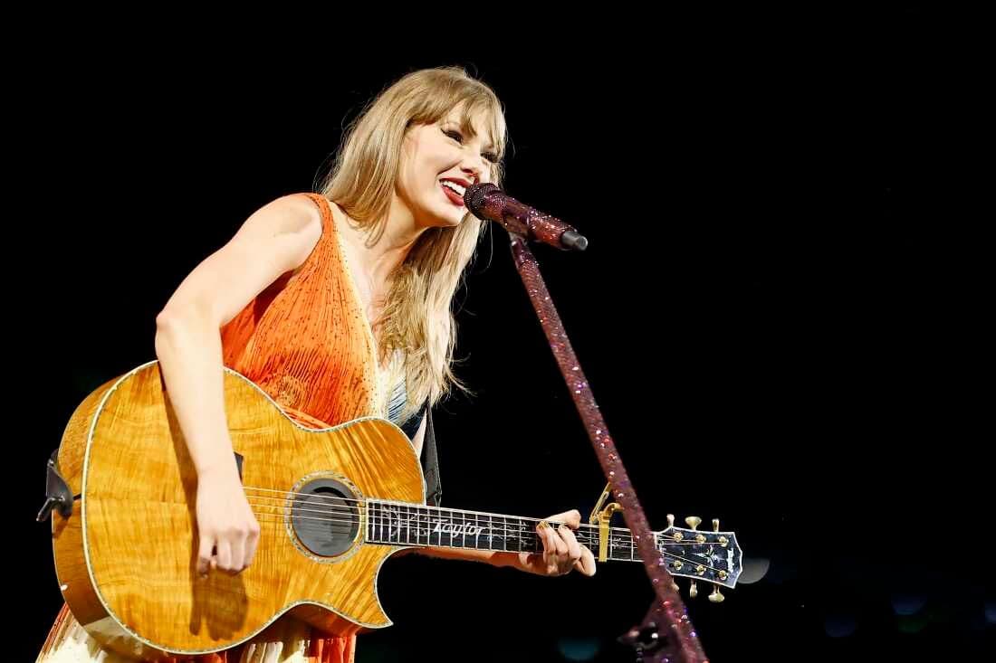 Taylor Swift biểu diễn trên sân khấu với cây đàn guitar, thể hiện hình ảnh 'Showgirl' trong kỷ nguyên âm nhạc mới.