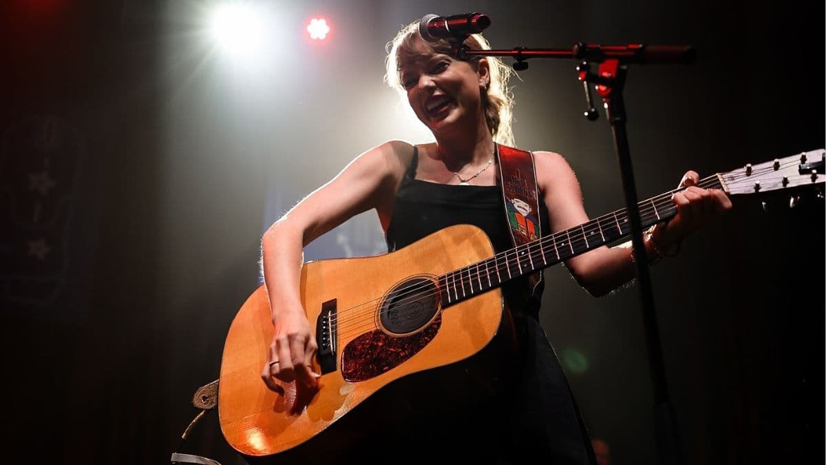 Taylor Swift biểu diễn trên sân khấu với cây đàn guitar, tượng trưng cho sự nghiệp âm nhạc rực rỡ của cô.