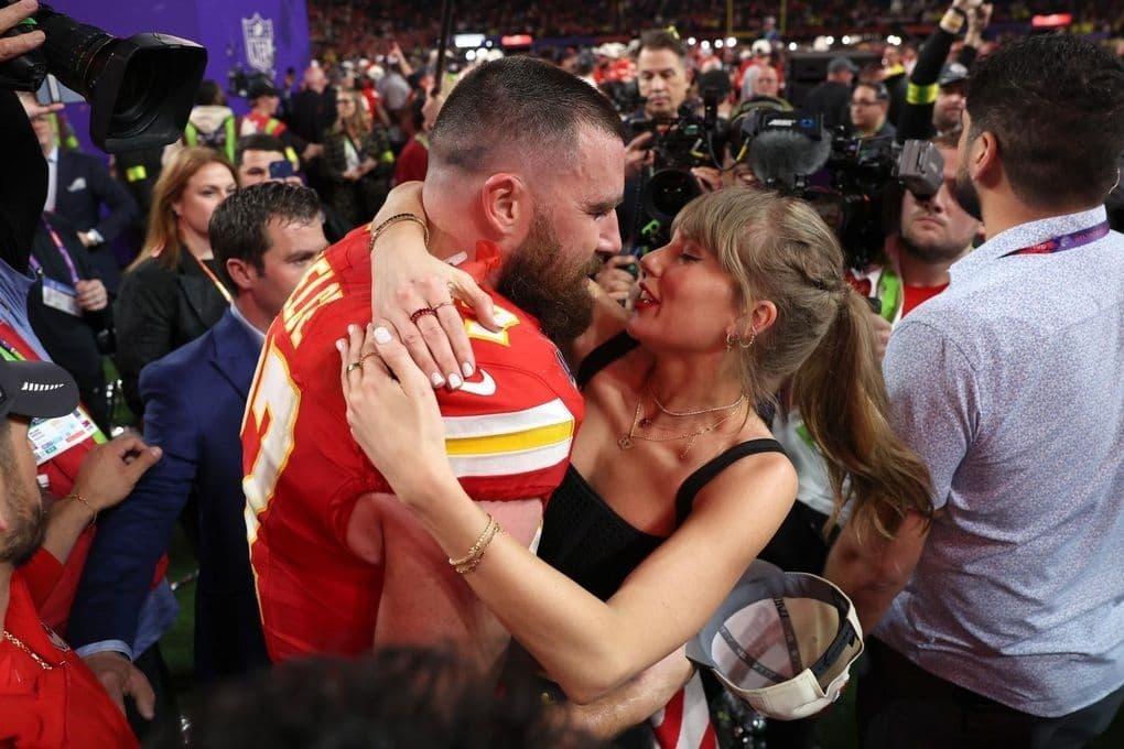 Taylor Swift và Travis Kelce ôm nhau trên sân bóng bầu dục, thể hiện sự ủng hộ lẫn nhau.