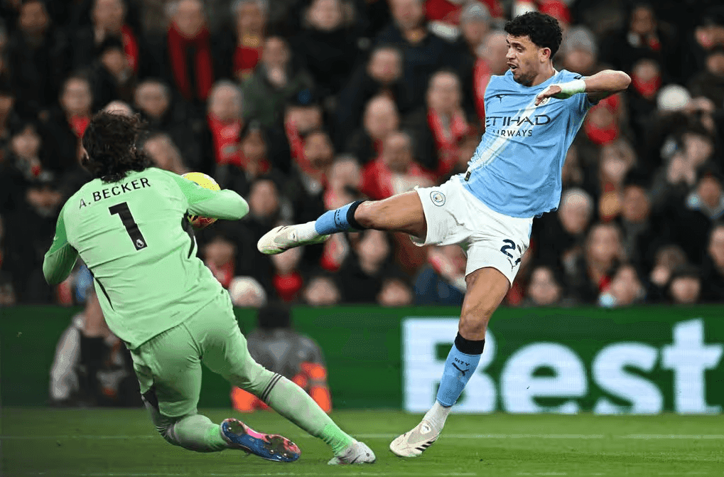 Thủ môn Alisson Becker của Liverpool cản phá cú sút từ cầu thủ Man City, thể hiện sự cạnh tranh của các đội bóng hàng đầu.
