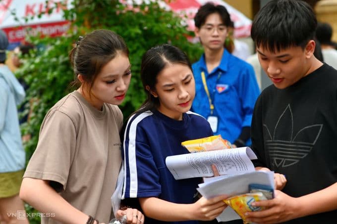 Thí sinh thi tại điểm trường THPT Trần Phú, Hà Nội, cùng người thân xem đề Toán sau khi hết giờ làm bài, chiều 26/6. Ảnh: Giang Huy