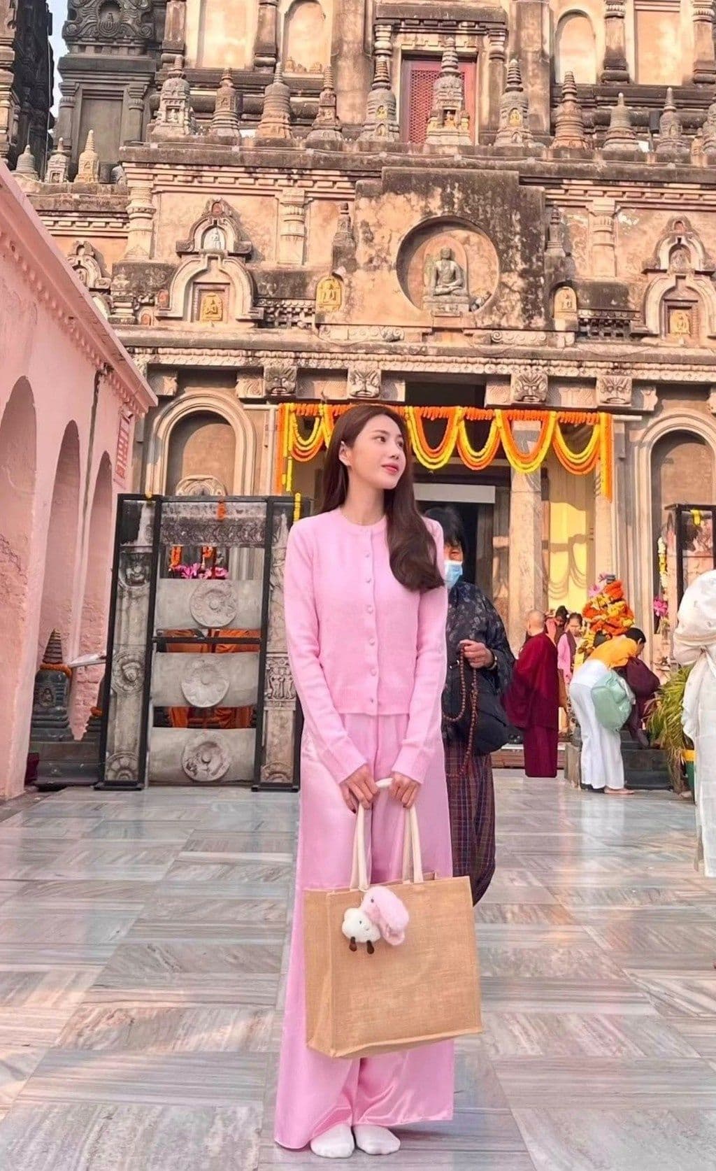 Thủy Tiên trong trang phục giản dị, đứng trước kiến trúc cổ, thể hiện sự tĩnh lặng và an yên trong cuộc sống ẩn dật.