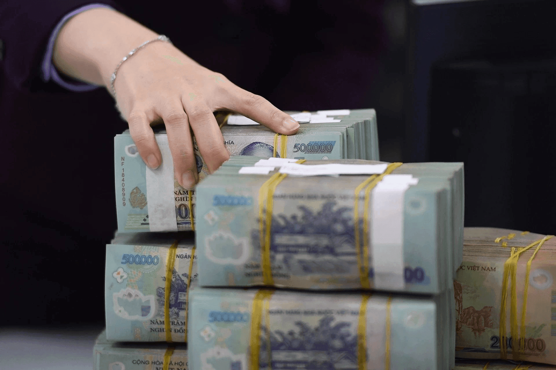 Tiền mặt được xếp chồng tại quầy giao dịch ngân hàng, minh họa cho sự dồi dào thanh khoản của hệ thống ngân hàng.