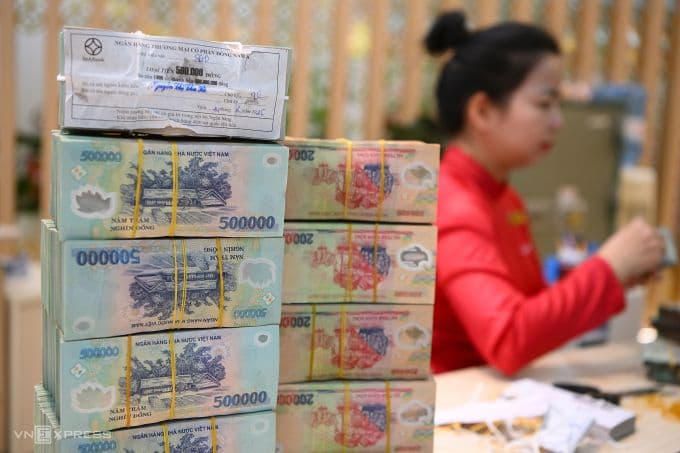 Tiền mặt mệnh giá 500.000 đồng xếp chồng trên bàn giao dịch ngân hàng, tượng trưng cho dòng tiền và thanh khoản trong hệ thống tài chính Việt Nam.