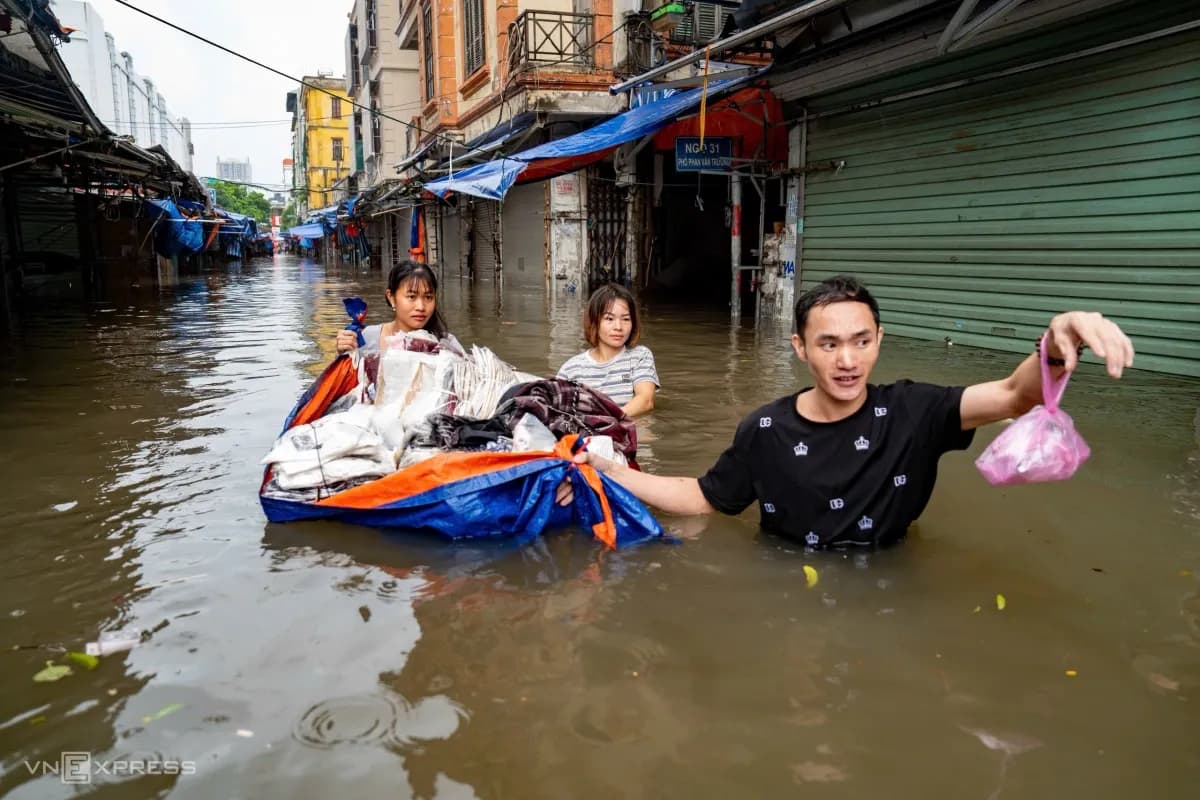 Tiểu thương dùng bạt làm 'thuyền' vận chuyển hàng hóa trong chợ Nhà Xanh ngập lụt, thể hiện sự kiên cường và khả năng thích nghi của người dân Hà Nội.