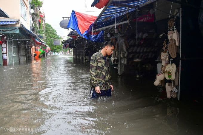 Tiểu thương đứng trong biển nước ngập trước cửa hàng tại khu chợ Hà Nội.