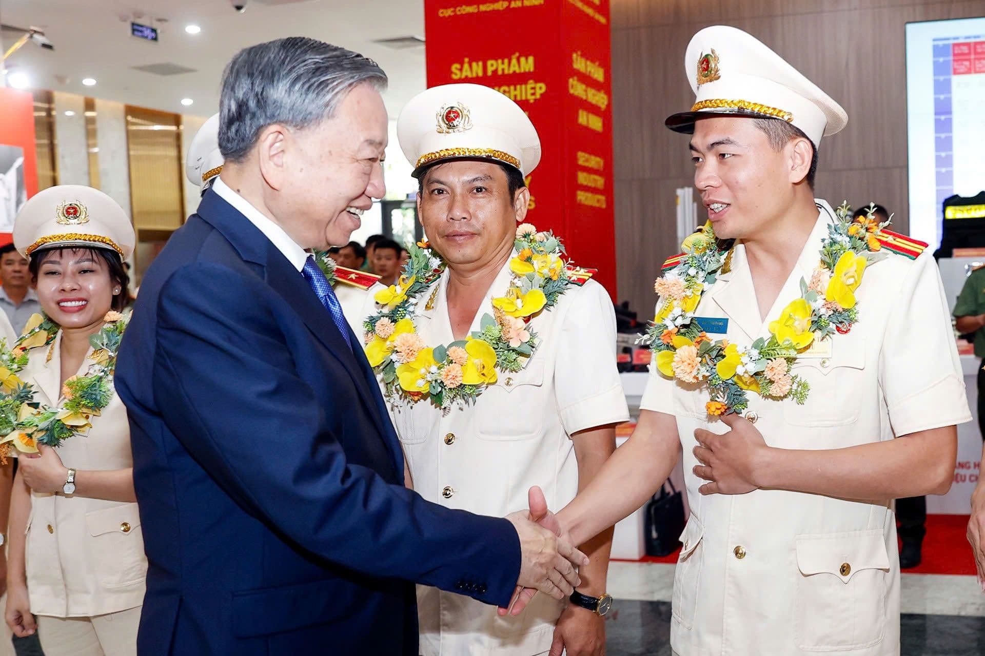 Tổng Bí thư Tô Lâm bắt tay cán bộ Công an, gần khu vực trưng bày sản phẩm công nghiệp an ninh