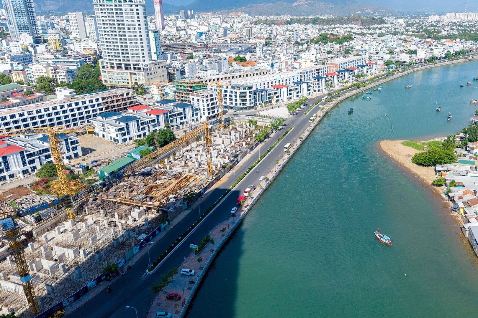 Toàn cảnh khu vực đô thị đang phát triển với các công trình xây dựng và tuyến đường ven sông, thể hiện sự chuyển mình của Cam Ranh thành trung tâm kinh tế biển.