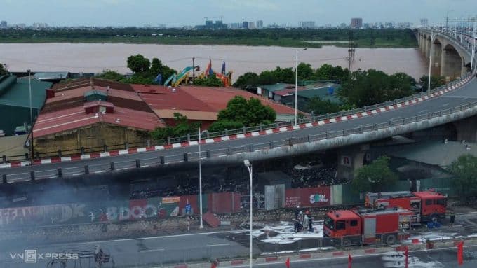 Toàn cảnh vụ cháy bãi xe dưới chân cầu Vĩnh Tuy, Hà Nội với khói đen và xe cứu hỏa.