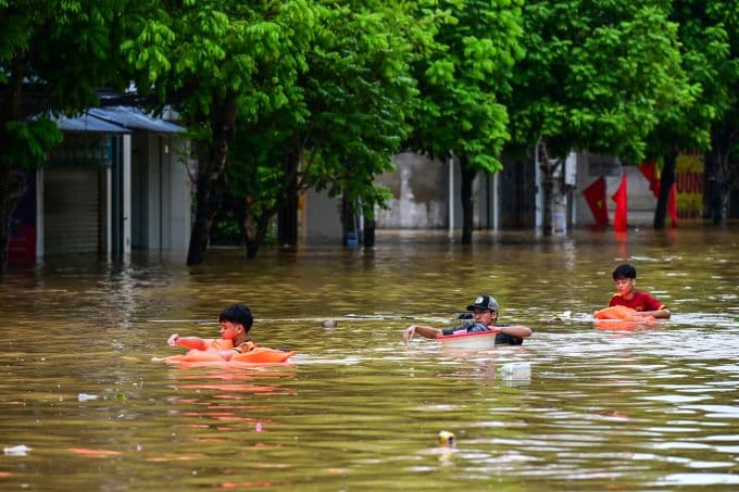Trẻ em bơi trên đường phố ngập lụt ở Lào Cai, hậu quả của lũ lụt sau bão Bualoi