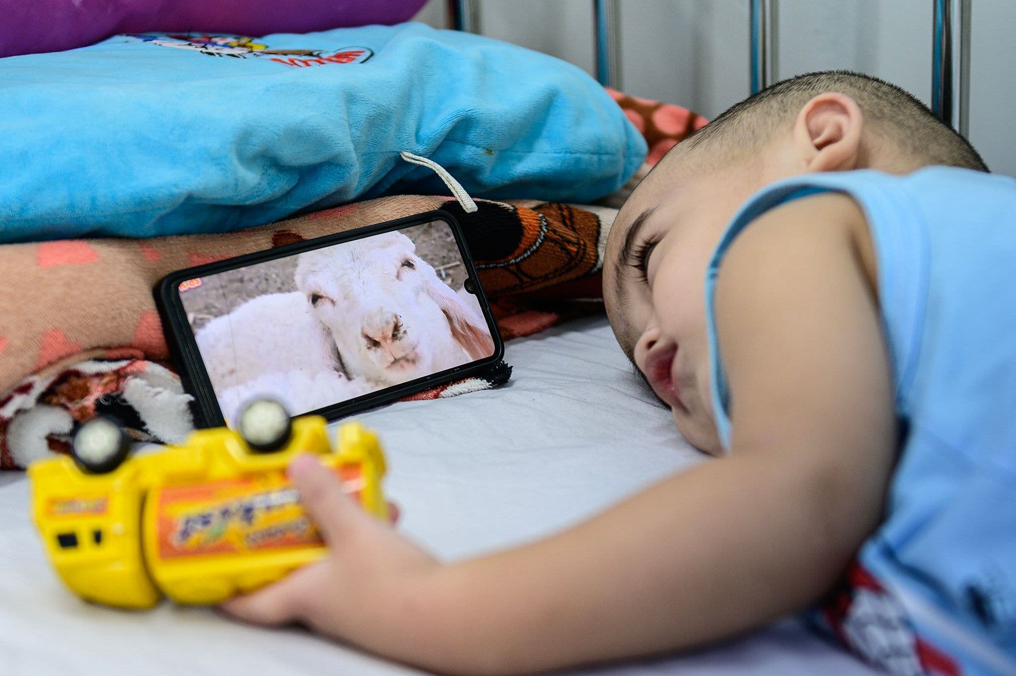 Trẻ nhỏ nằm trên giường bệnh, có thể đang trong giai đoạn khởi phát bệnh tay chân miệng