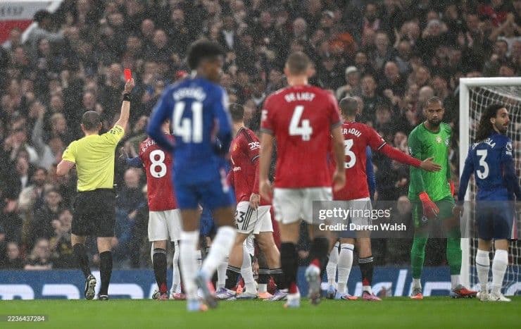 Trọng tài rút thẻ đỏ trong trận đấu giữa Manchester United và Chelsea, tượng trưng cho áp lực và 'án tử' mà HLV Amorim đang đối mặt.