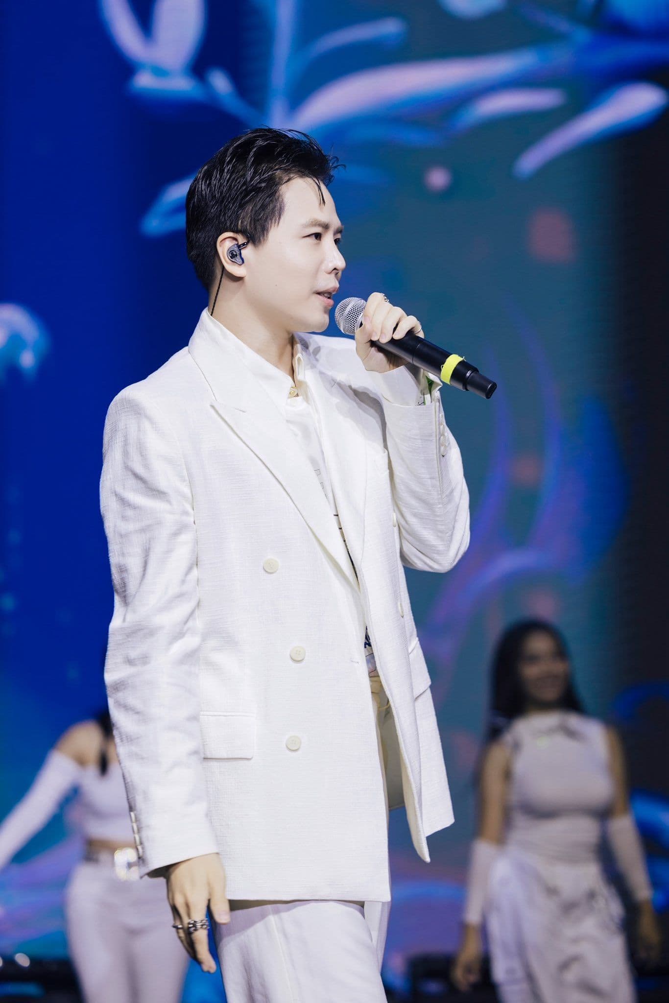 Trịnh Thăng Bình biểu diễn trên sân khấu trong bộ vest trắng, thể hiện ánh hào quang của một ca sĩ.