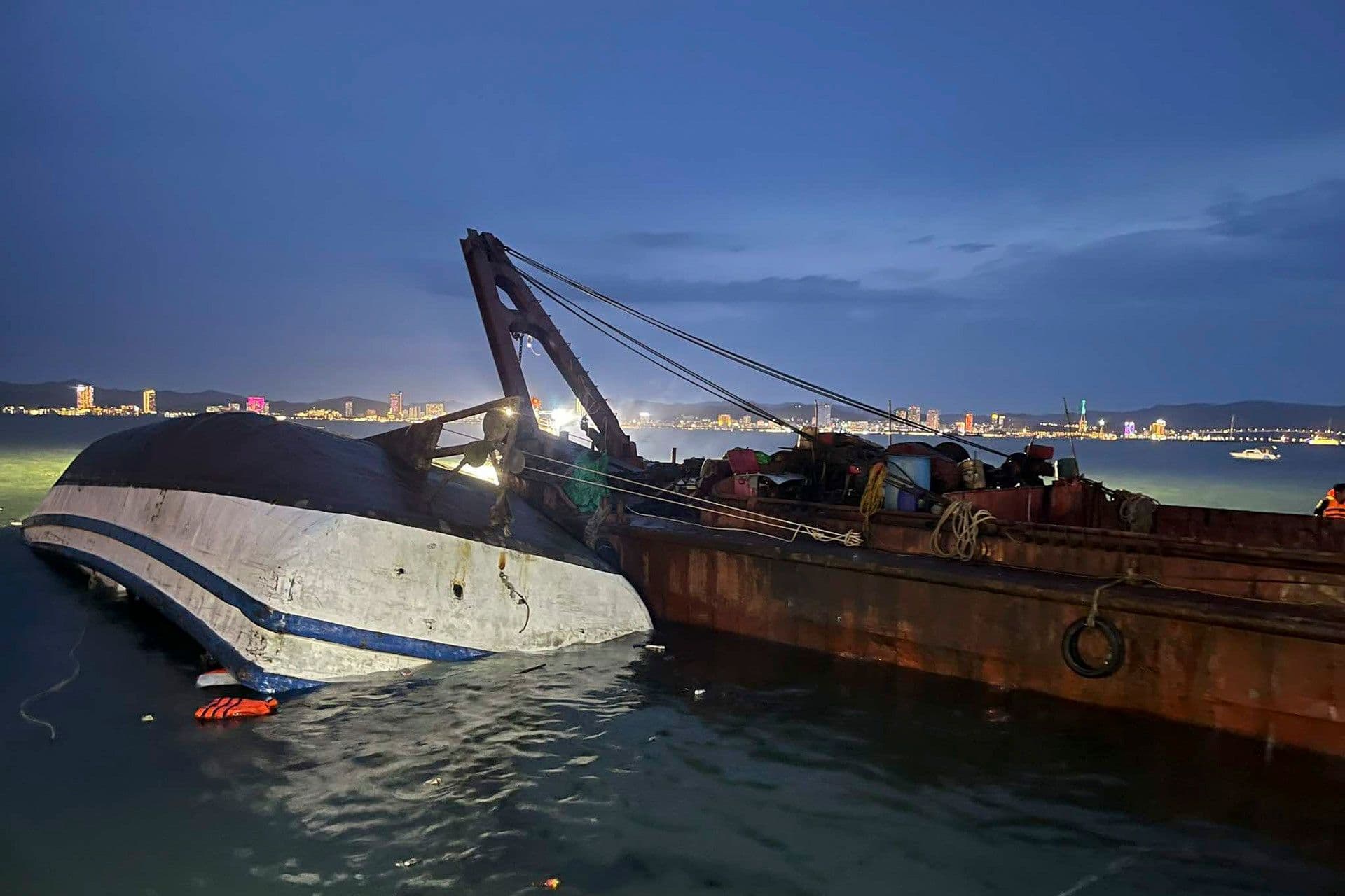 Tàu du lịch bị lật úp trên vịnh Hạ Long vào buổi tối, bên cạnh tàu cứu hộ.