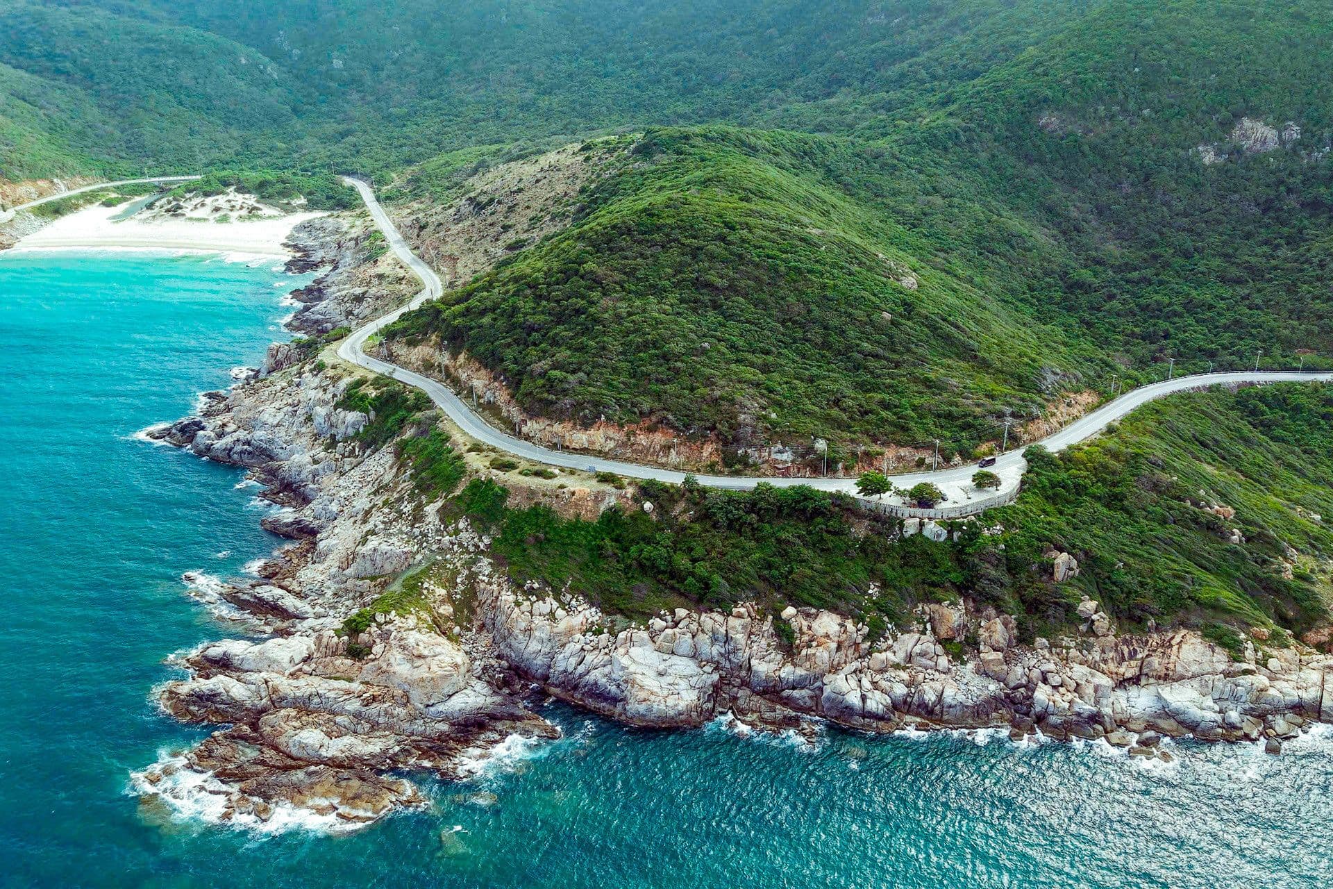 Tuyến đường ven biển uốn lượn qua sườn núi xanh, tượng trưng cho dự án cơ sở hạ tầng đột phá tại Cam Ranh.