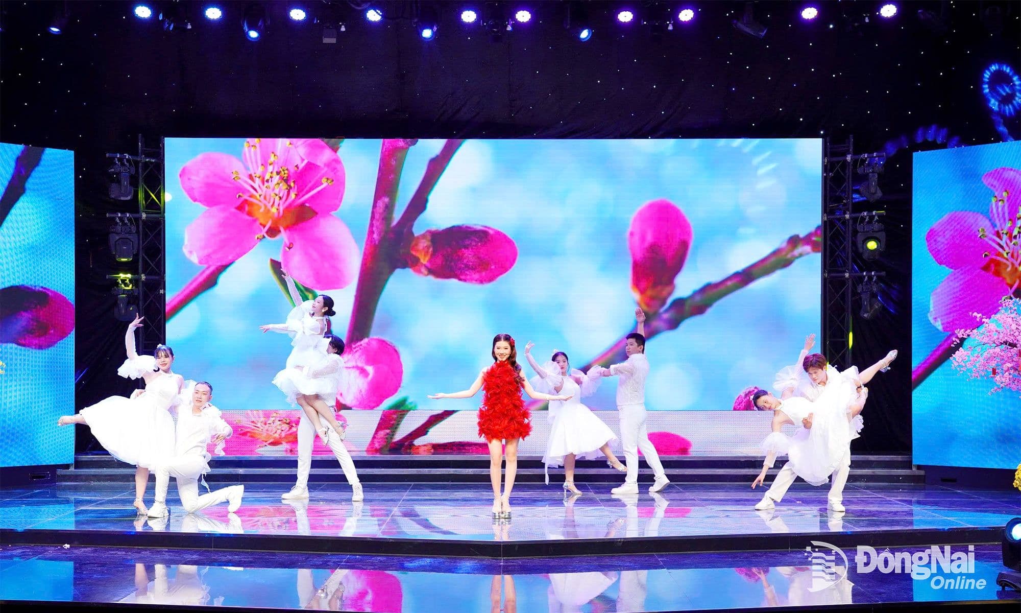 Vũ đoàn biểu diễn trên sân khấu hiện đại với phông nền hoa anh đào, thể hiện sự trẻ hóa và giao thoa của nhạc xuân.