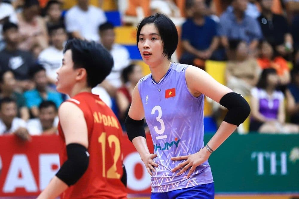 Vận động viên bóng chuyền nữ Việt Nam số 3 với lá cờ tổ quốc trên áo, thể hiện sự quyết tâm và niềm tự hào dân tộc.