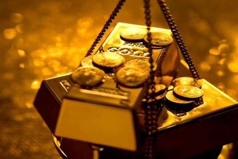 Vàng miếng và tiền xu trên cân, biểu tượng cho giá trị và sự biến động của thị trường vàng
