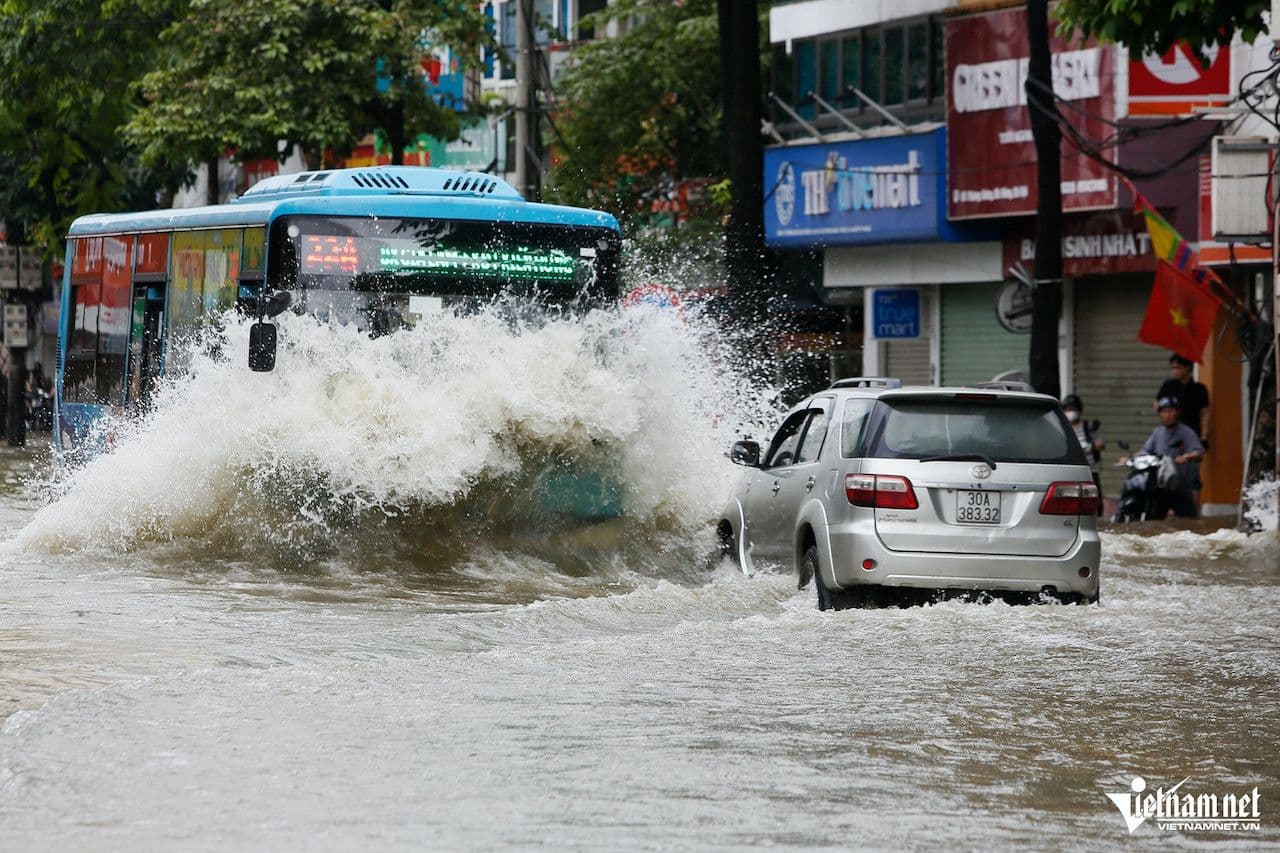 Xe buýt và ô tô di chuyển khó khăn trên đường phố Hà Nội ngập nước sau mưa lớn.