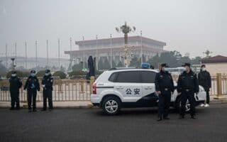 Xe cảnh sát và các sĩ quan an ninh tại một địa điểm quan trọng ở Trung Quốc, thể hiện sự kiểm soát chặt chẽ của nhà nước và sự thiếu minh bạch trong các vụ án chính trị.