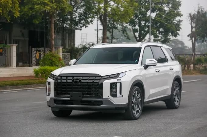 Xe Hyundai Palisade màu trắng đang lăn bánh trên đường phố Hà Nội, minh họa cho chiến lược giảm giá sâu của hãng xe.
