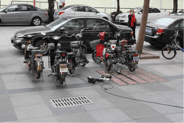 Xe máy điện đang sạc trên vỉa hè ở Trung Quốc, minh họa cho chiến lược chuyển đổi phương tiện.