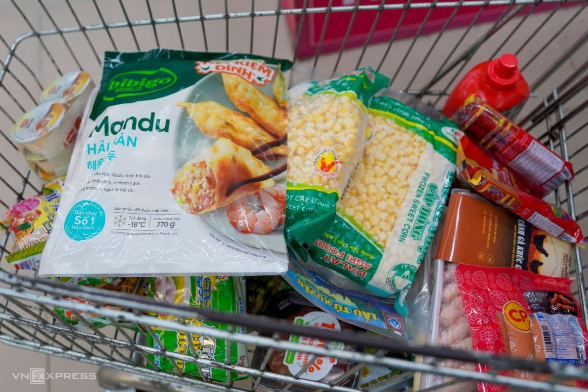 Xe đẩy siêu thị chứa đầy thực phẩm thiết yếu như mì gói, bắp đông lạnh, xúc xích, thể hiện sự chuẩn bị cho khả năng chống chịu lâu dài.